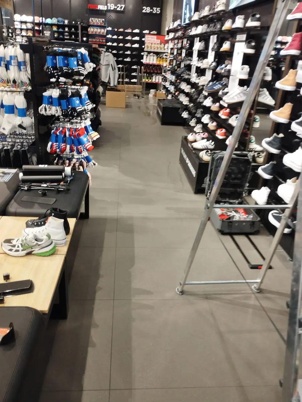 Surface de vente d'une boutique de sport à Mondeville après nettoyage fin de chantier, sol carrelé propre et rayonnages de chaussures